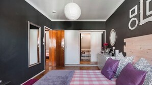 Un dormitorio con una colcha a cuadros, cabecero de madera y un espejo grande en la pared.