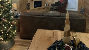 A cozy cabin interior with a wooden interior, a fireplace, a television, and a Christmas tree. - Excellent Mountain View’s, Hot Tub, WIFI, Minutes to Gatlinburg (Gatlinburg)