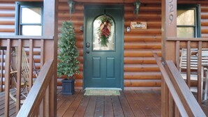 A wooden cabin with a green door, a Christmas tree, and a welcome sign. - Excellent Mountain View’s, Hot Tub, WIFI, Minutes to Gatlinburg (Gatlinburg)