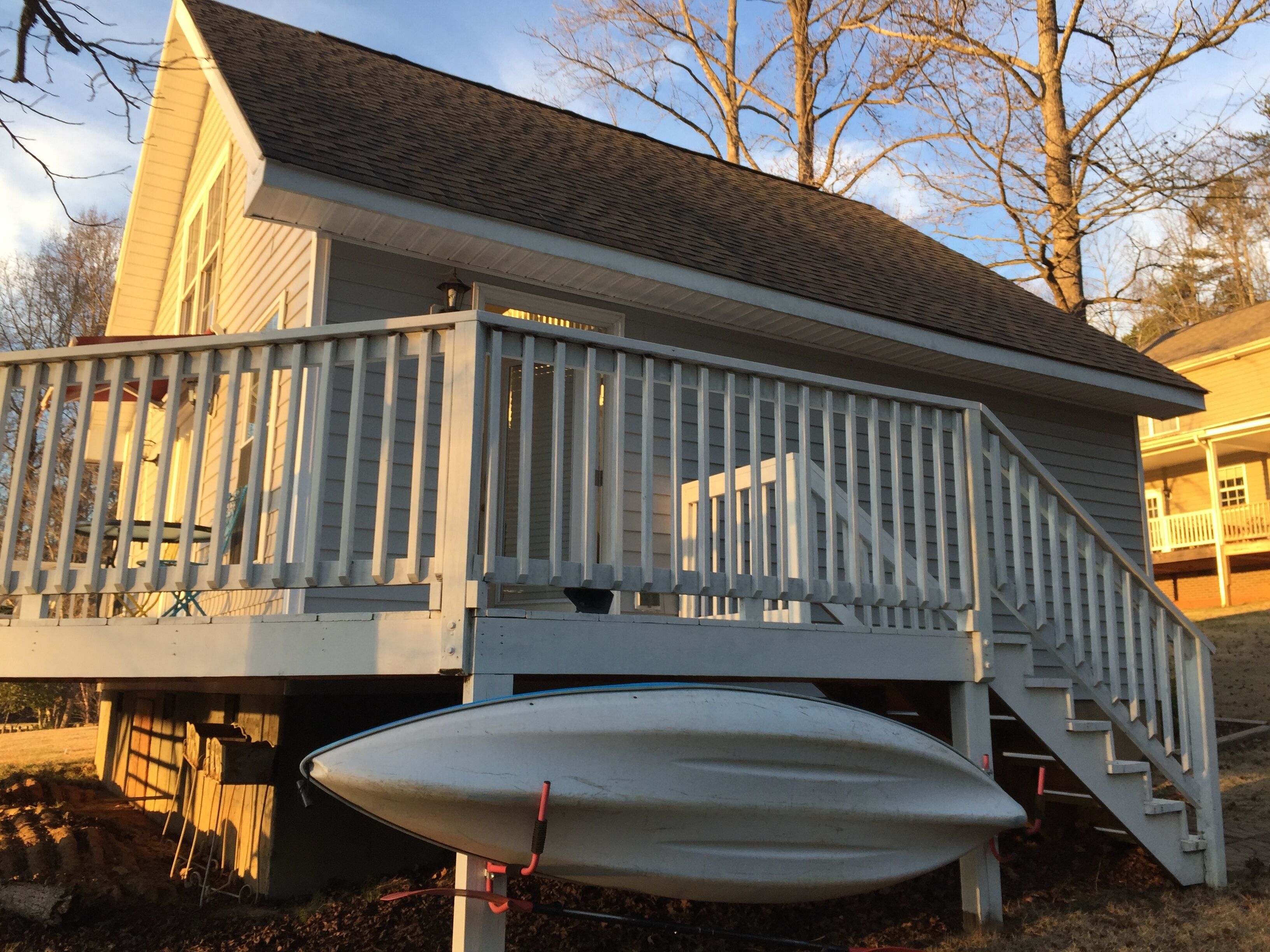 A house with a deck, a staircase, and a boat.