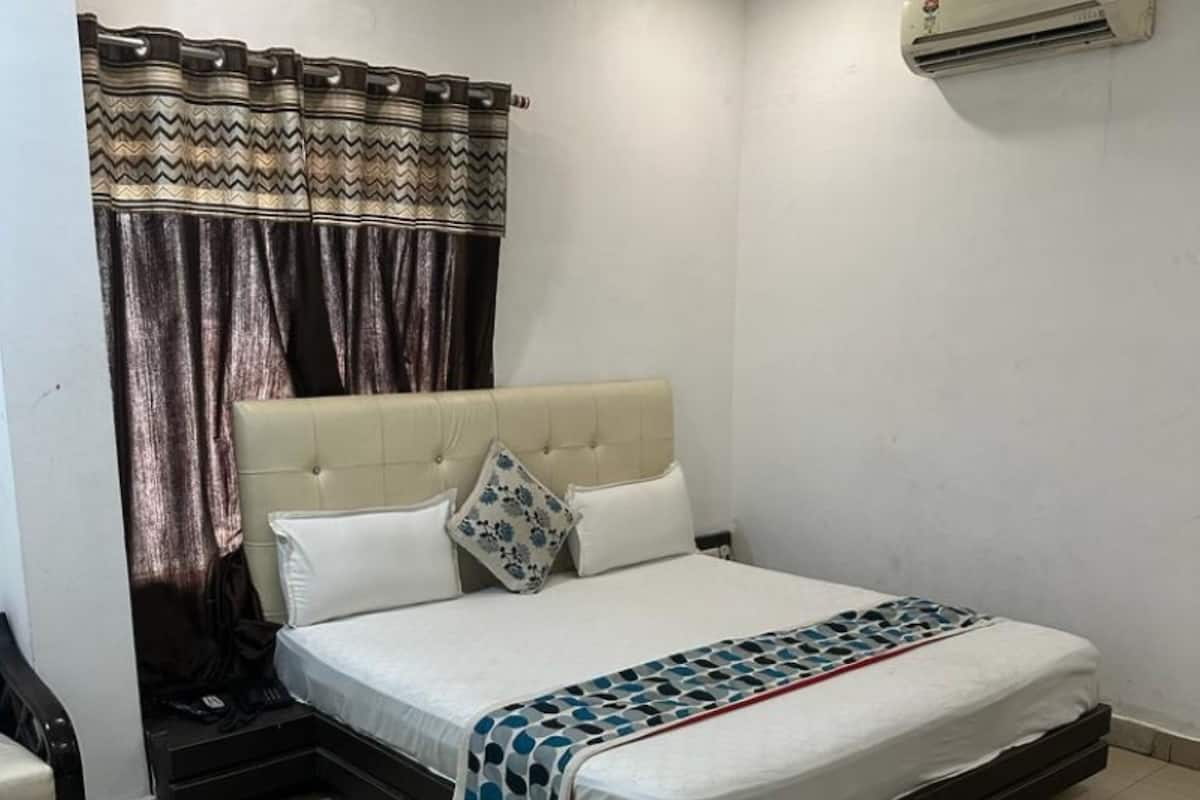 A bedroom with a bed, curtains, a ceiling fan, and an air conditioning unit.