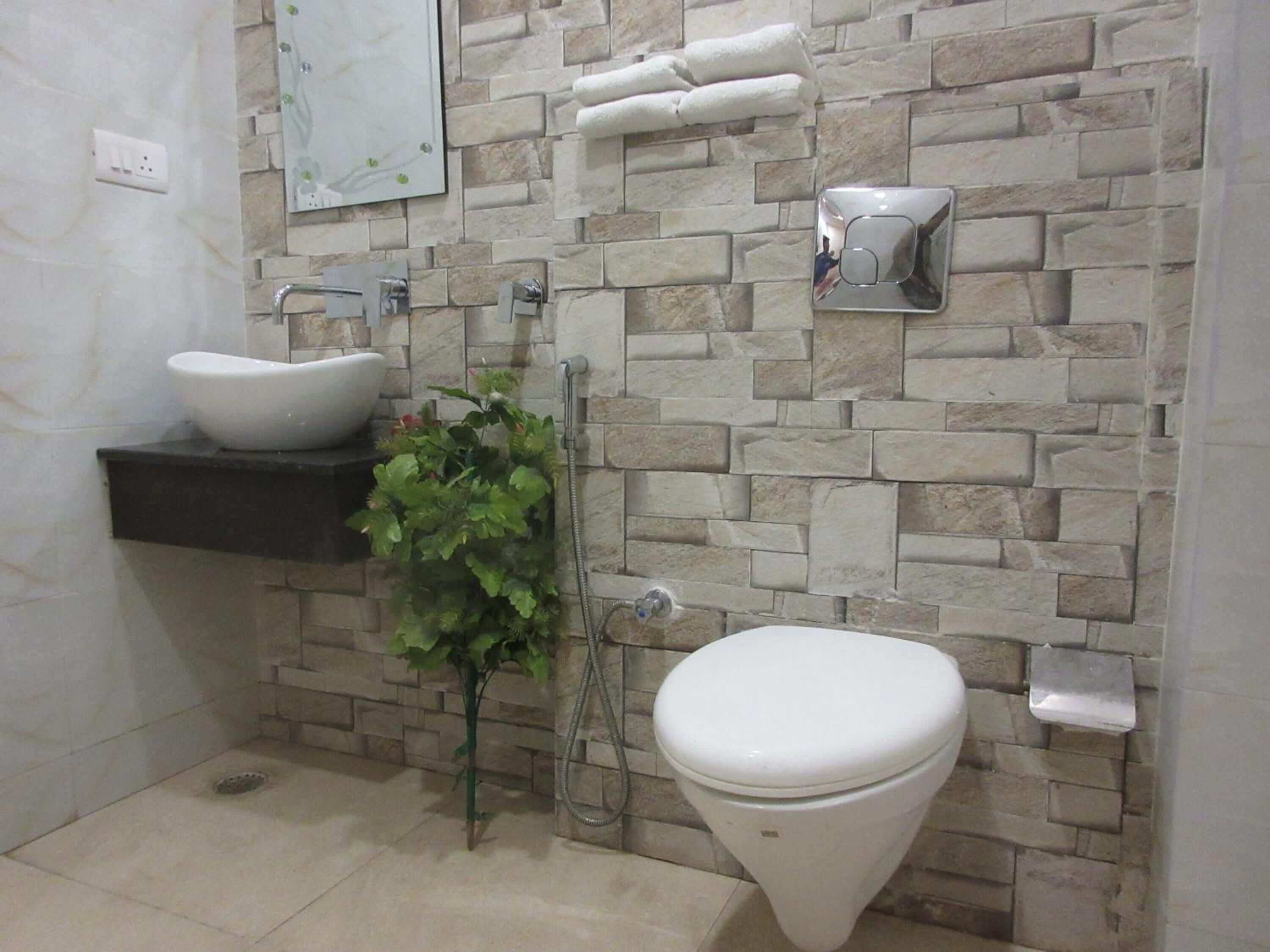 A bathroom with a stone wall, a white sink, a toilet, and a shower.