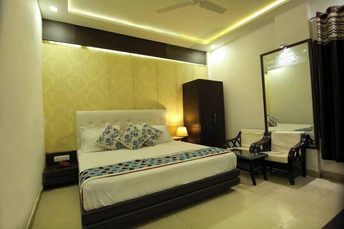 A hotel room with a large bed, a wardrobe, a desk, and a mirror.