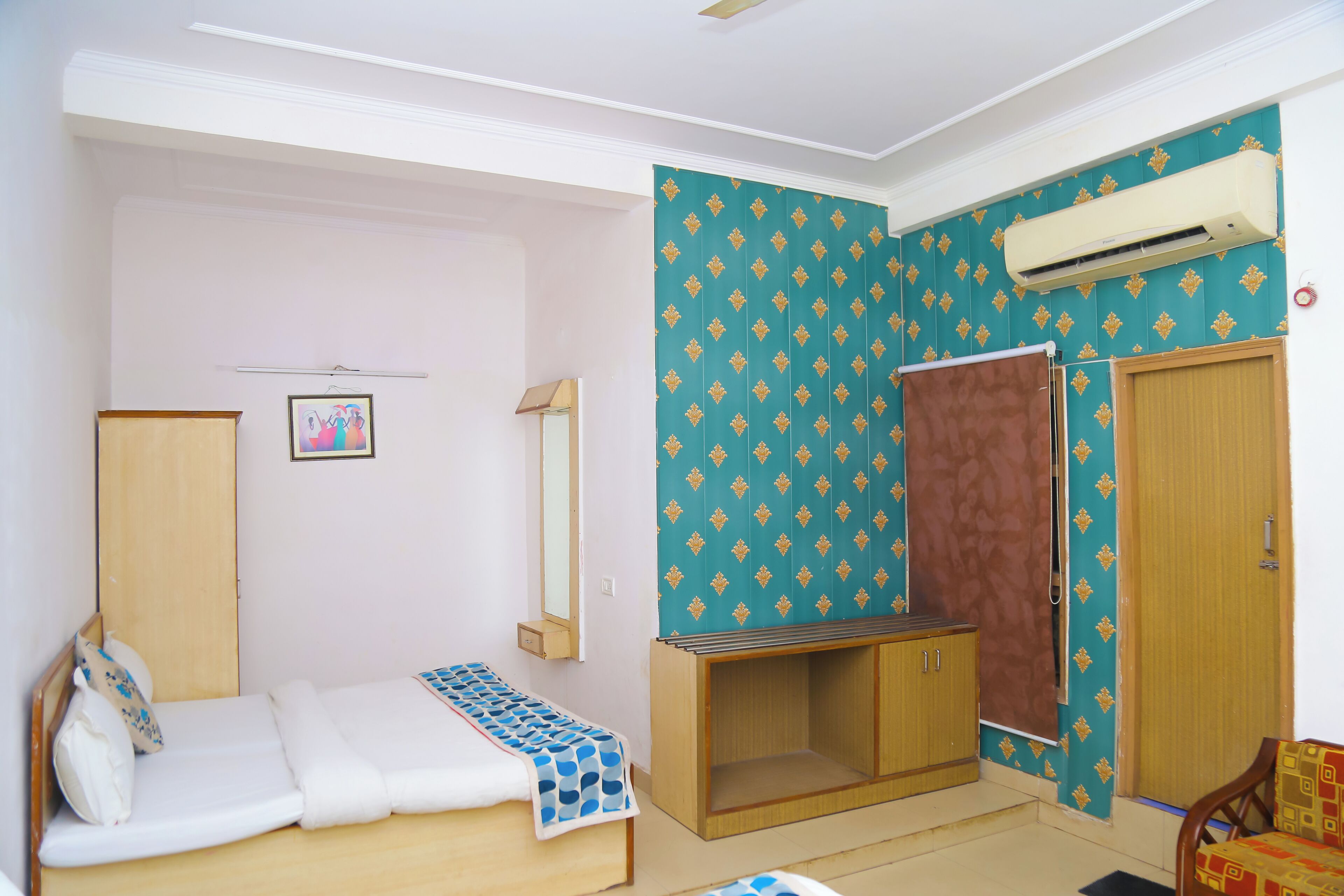 Een kamer met een bed, een kledingkast, een klein tafeltje en een airconditioning.