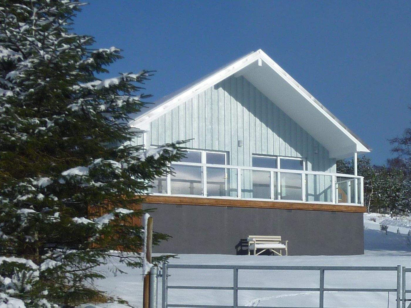 A modern building with a sloped roof, large windows, and a balcony.