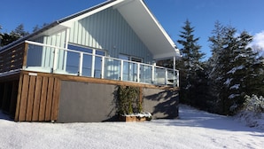 A modern two-story house with a balcony, surrounded by snow-covered trees. - Torran View (Inverness)
