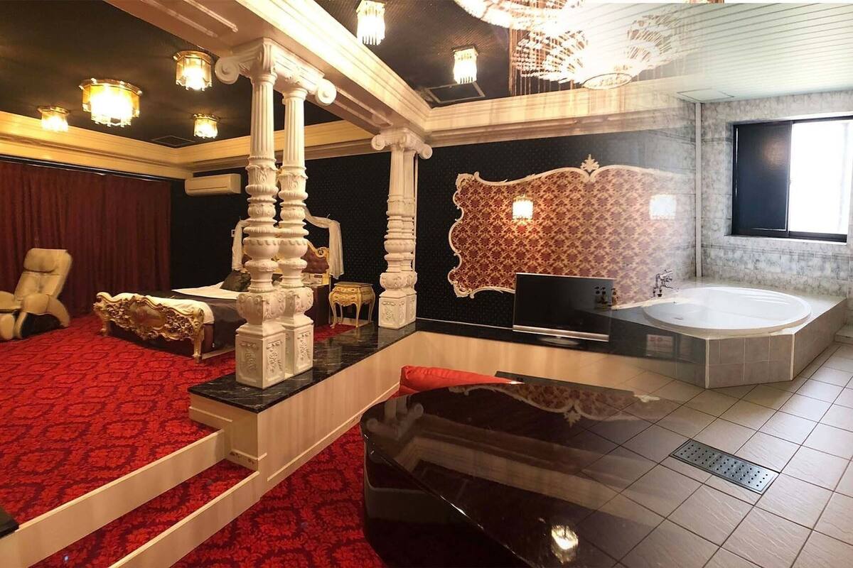 A luxurious room with a red carpet, a grand staircase, a large bathtub, and a chandelier.