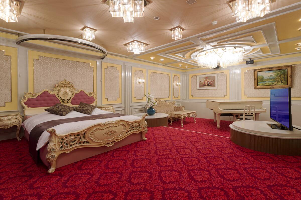 A luxurious bedroom with a large ornate bed, a desk, and a television.