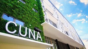 A building with a green vertical garden and the name 'CUNA' on the facade. - Cuna Hotel (El Nido)