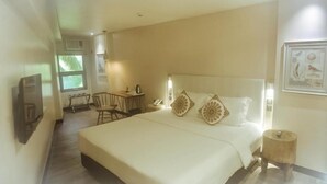 A hotel room with a large bed, a desk with a chair, a small table, and a window. - Cuna Hotel (El Nido)