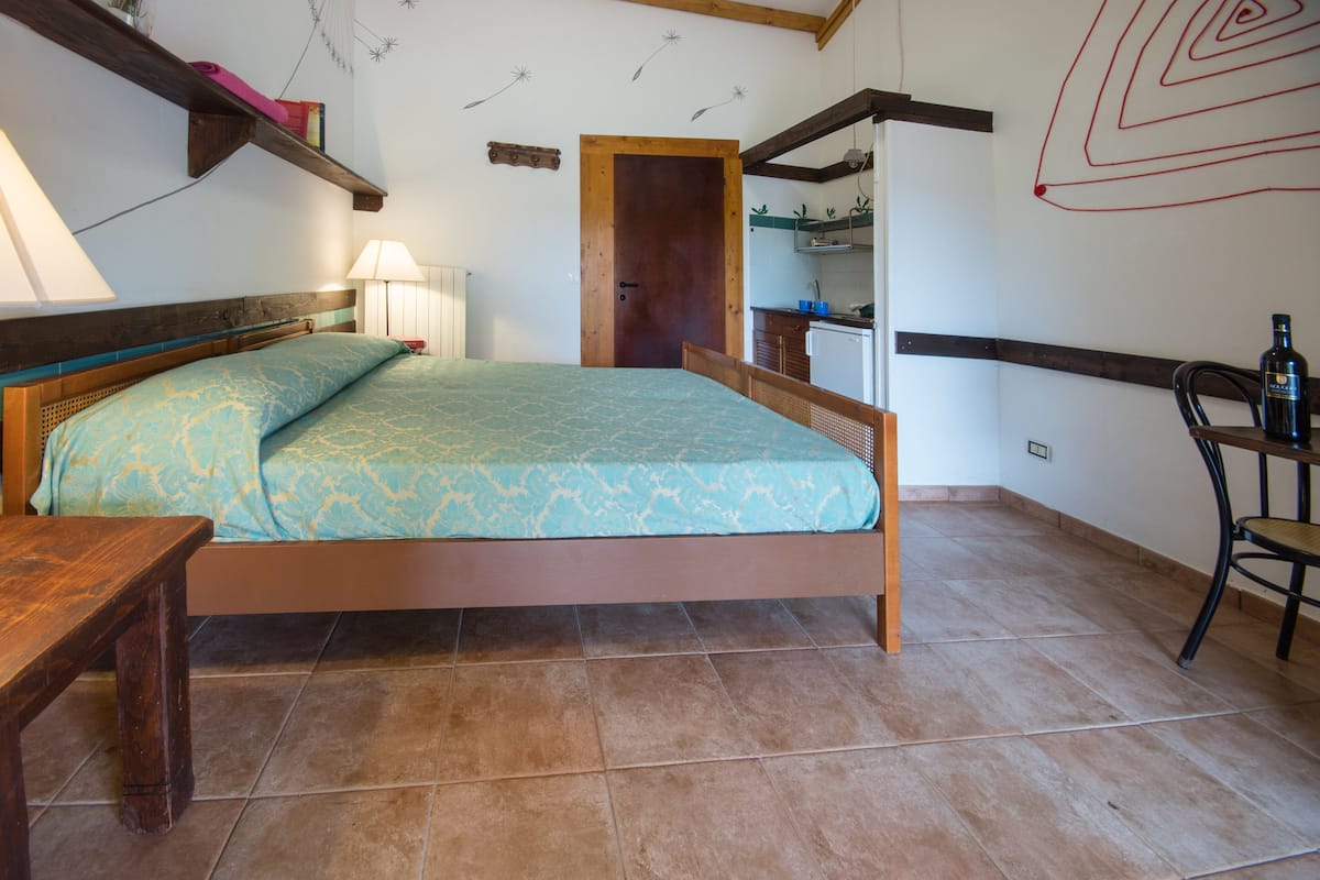 Ein Schlafzimmer mit Bett, Nachttisch, Lampe und einer Holztür zu einem Badezimmer.