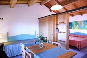 A room with a bed, a table with a vase of flowers, and a painting on the wall.