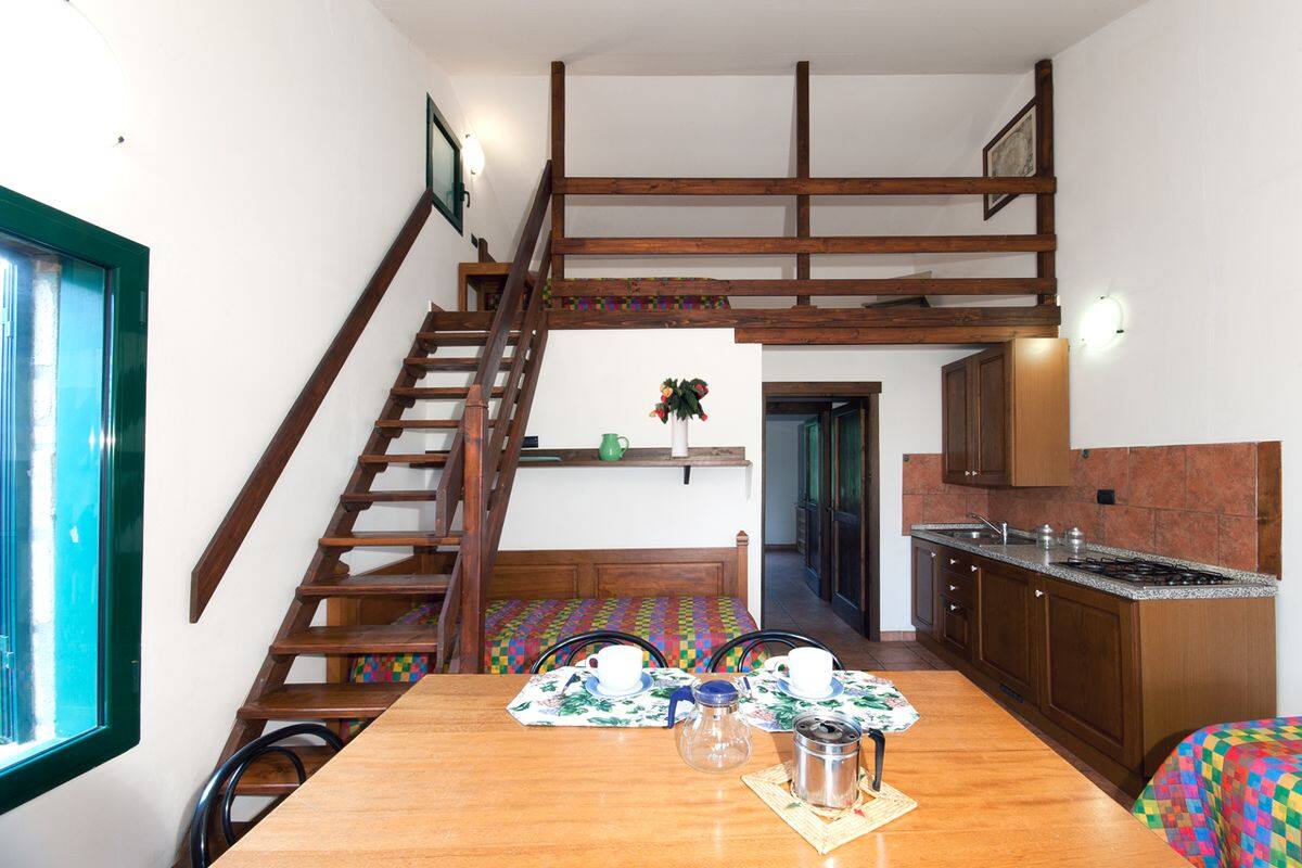 Eine Küche mit Holzausstattung, einem Esstisch mit Stühlen und einer Treppe, die in einen oberen Bereich führt.