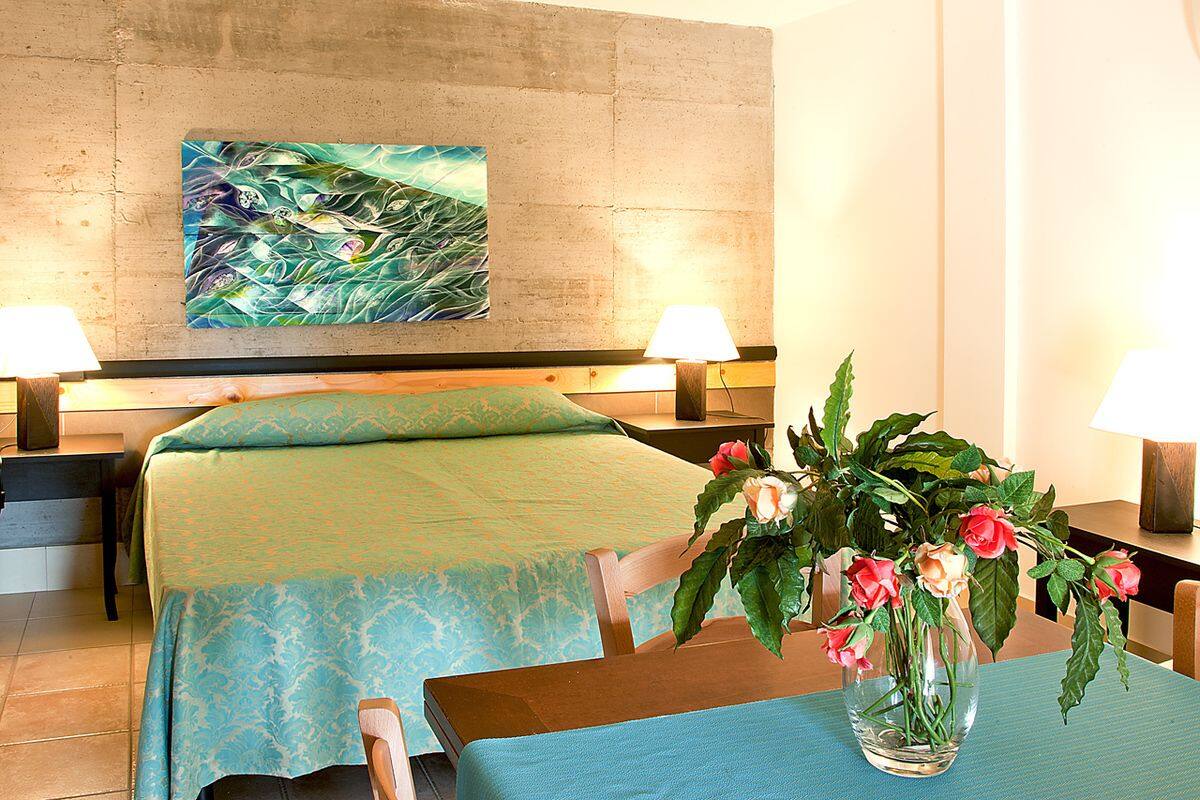 Ein Hotelzimmer mit zwei Betten, einem großen abstrakten Gemälde an der Wand und einem Tisch mit Blumen in einer Vase.