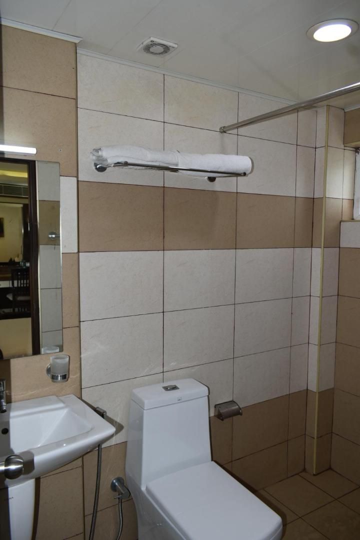 A bathroom with a toilet, sink, and a towel rack.