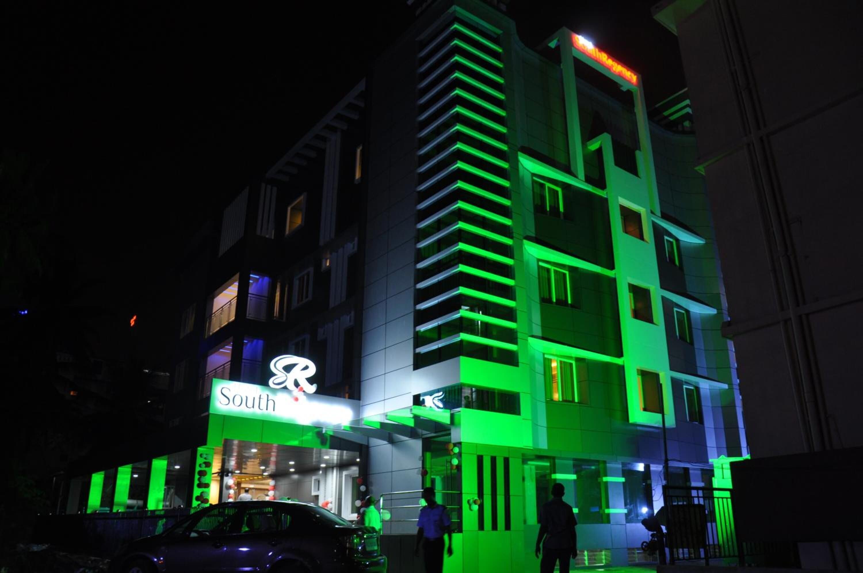 A multi-story building with a prominent 'South' sign, featuring a modern architectural design with green lighting accents.