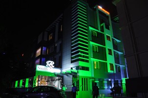 Un edificio de varios pisos con un letrero llamativo que dice 'South', que presenta un diseño arquitectónico moderno con detalles de iluminación verde.