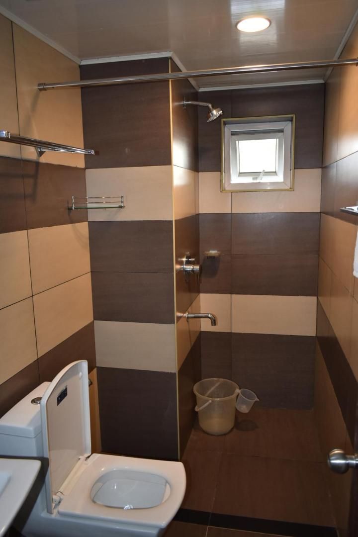 A compact bathroom with a toilet, a shower area, and a small window.