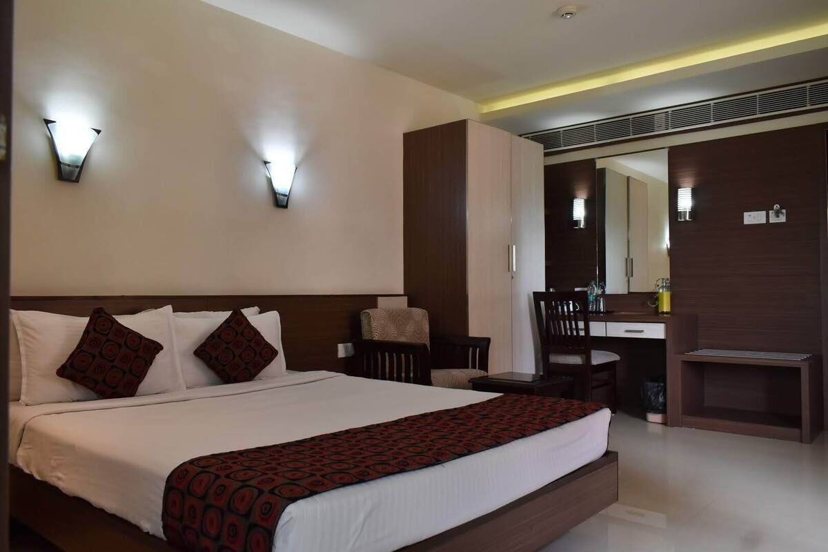 A hotel room with a large bed, two bedside tables, a desk, and a chair.