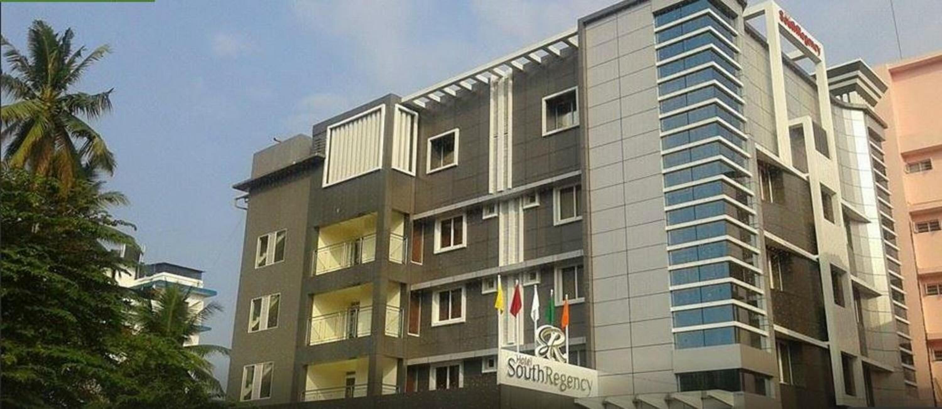 Un hotel de varios pisos con balcones, un letrero que dice 'Hotel SouthRegency' y banderas.