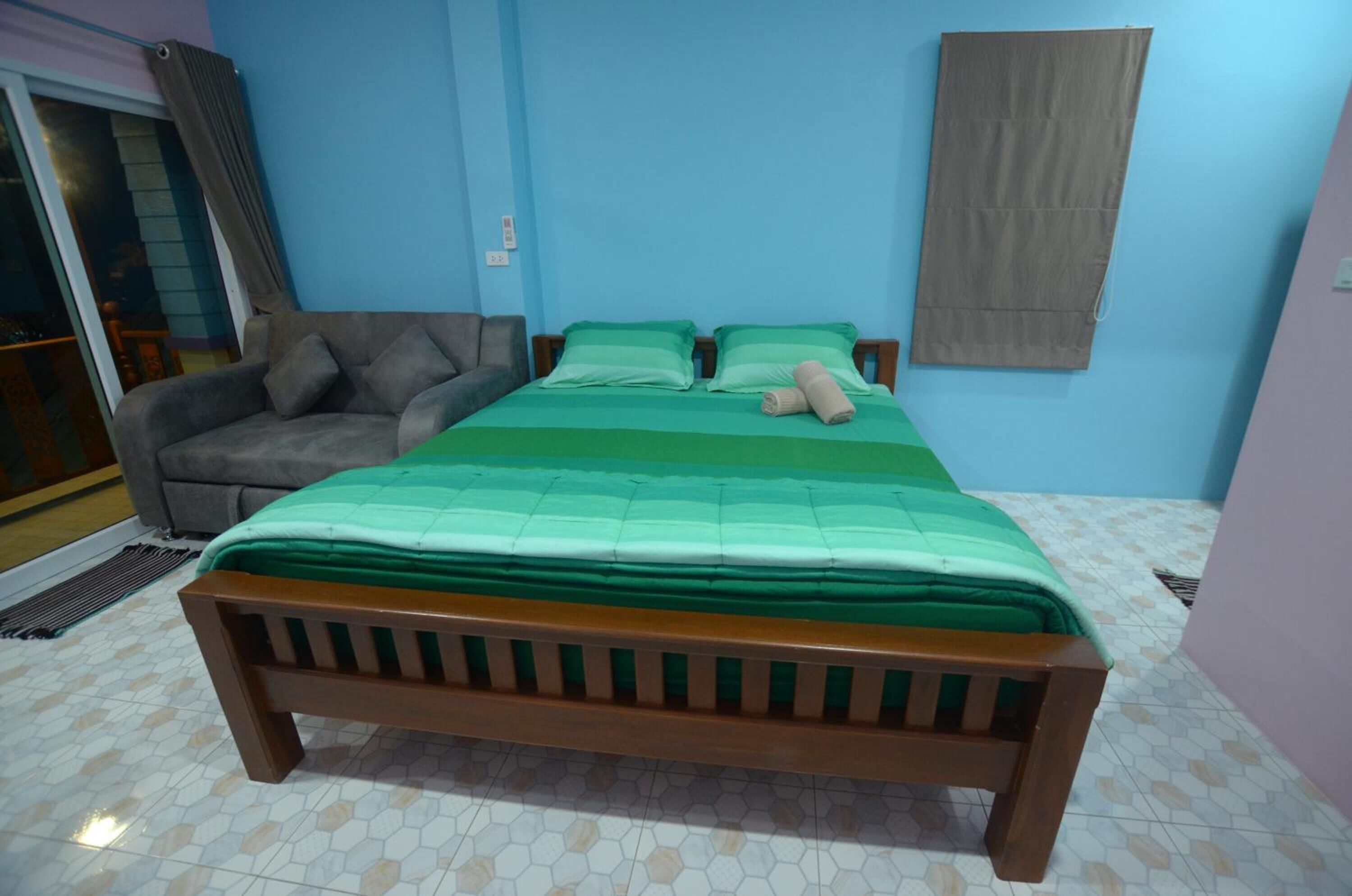 A bedroom with a bed, a sofa, and a curtain.