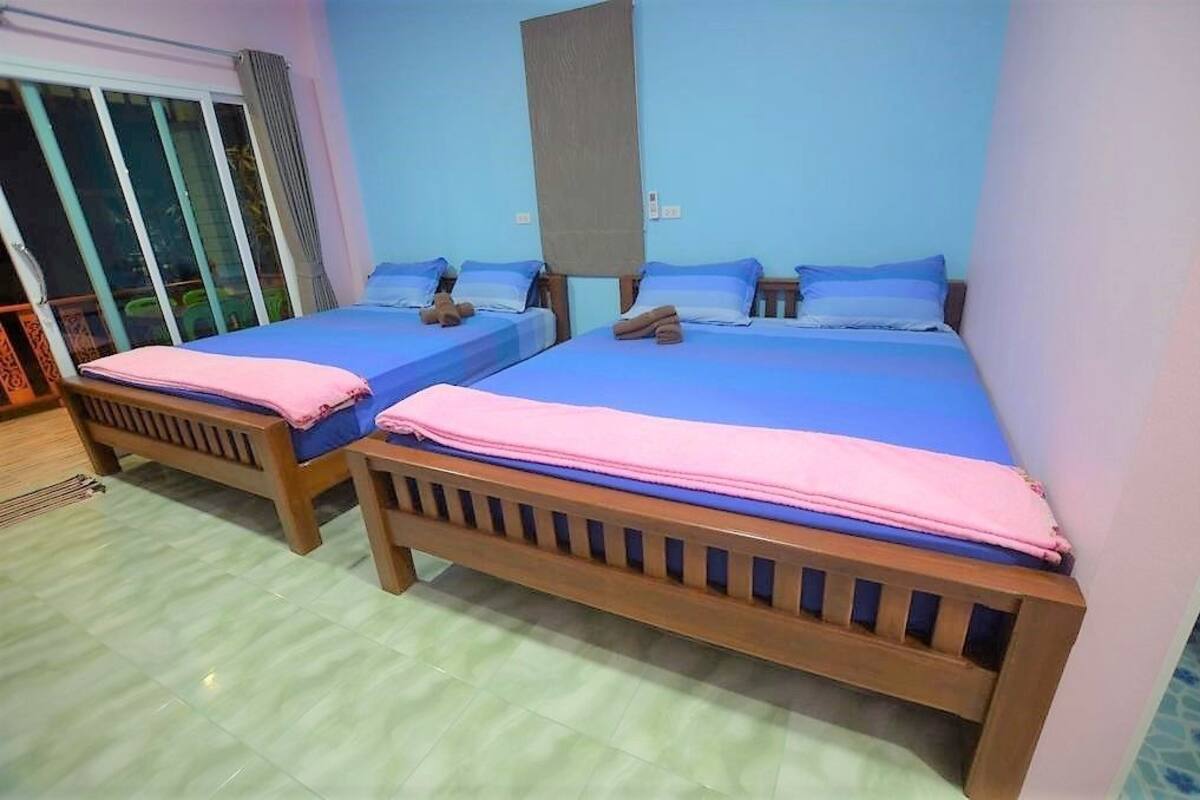 A room with two wooden beds, each with a blue mattress and pink bedding.