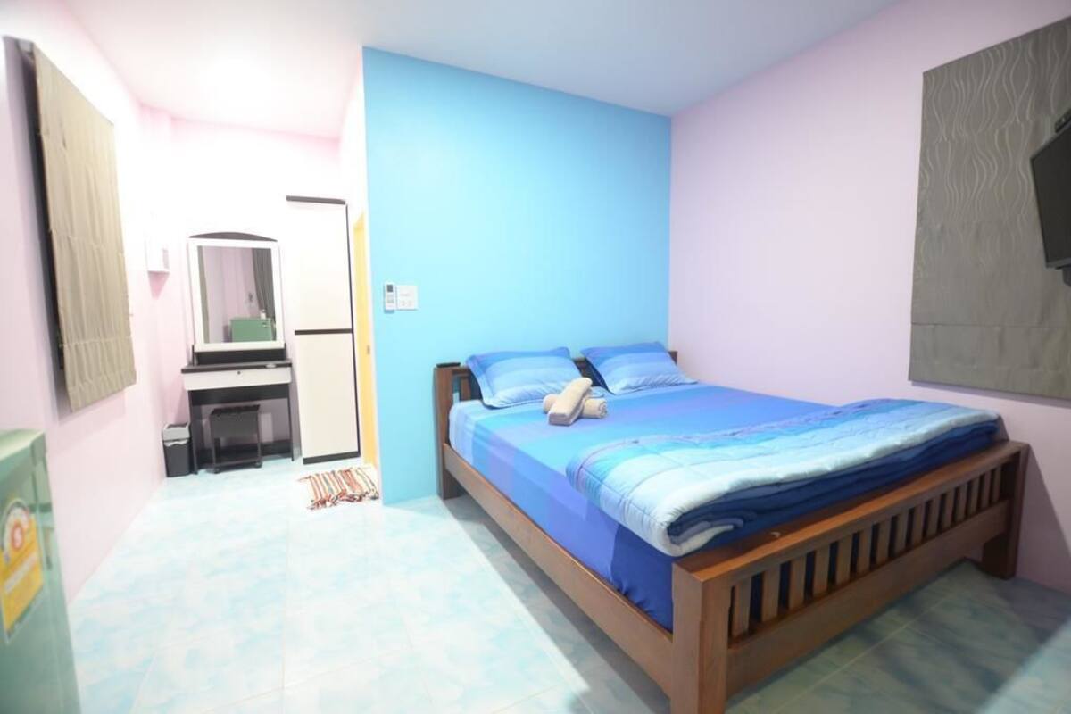 A bedroom with a bed, a desk, and a mirror.