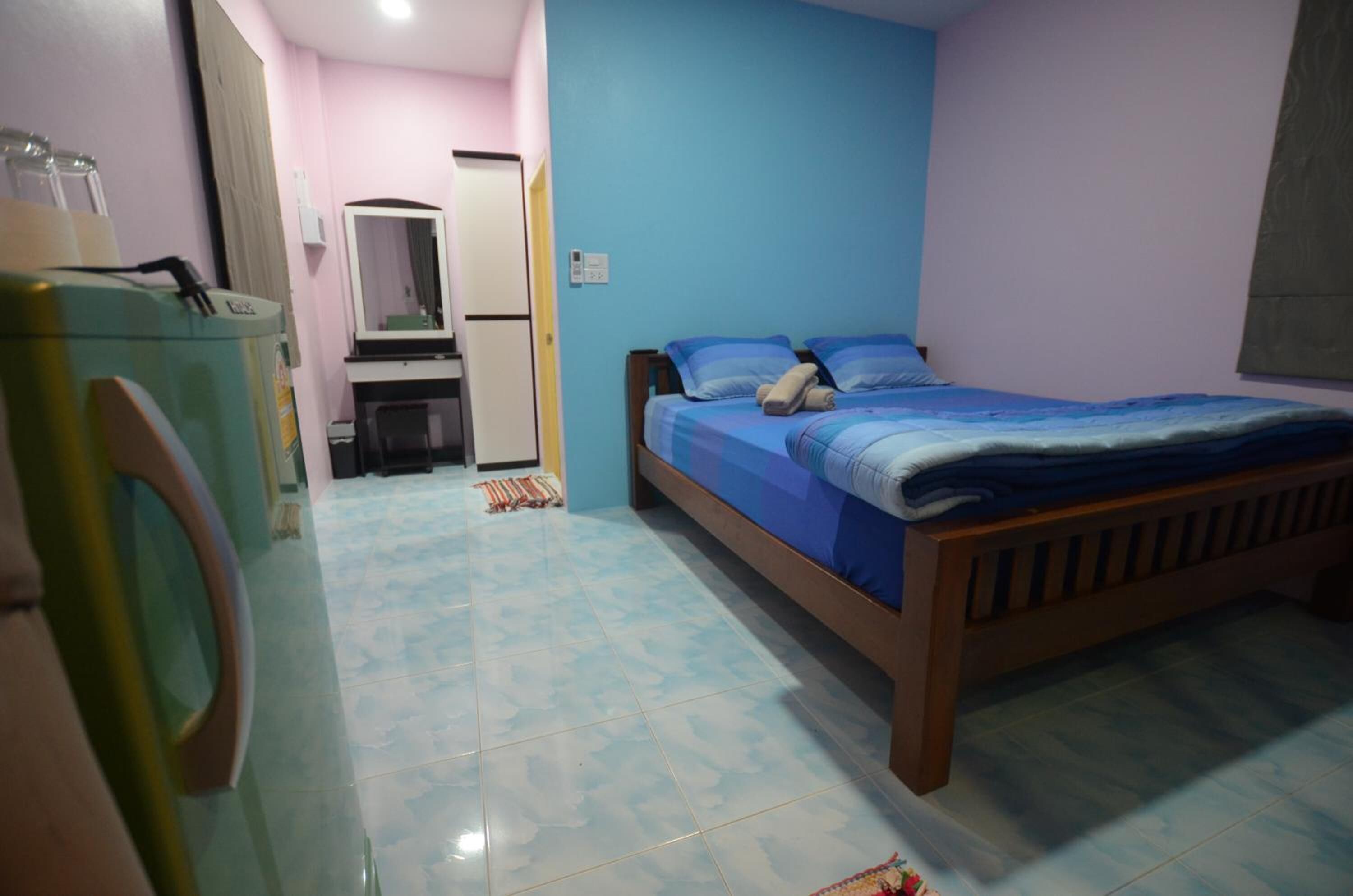 A bedroom with a bed, a dresser, a mirror, and a door leading to another room.