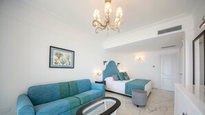 A modern living room with a blue sofa, a glass coffee table, and a bed with a blue headboard. - Villa Amore (Ravello)