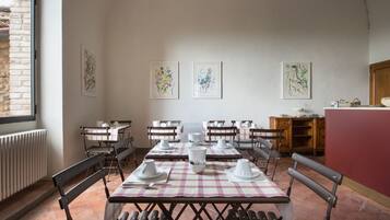 A dining area with tables set for four, chairs, and artwork on the walls.