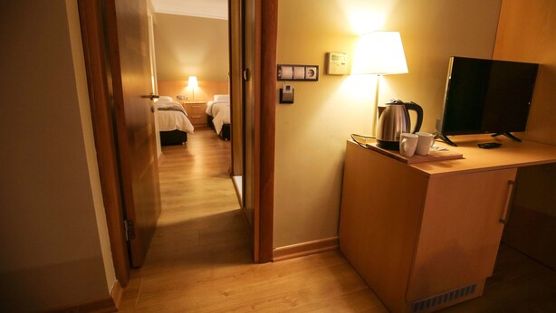 A hotel room with a wooden desk, a television, a lamp, and a bed with white bedding. - Artika Hotel (Istanbul)