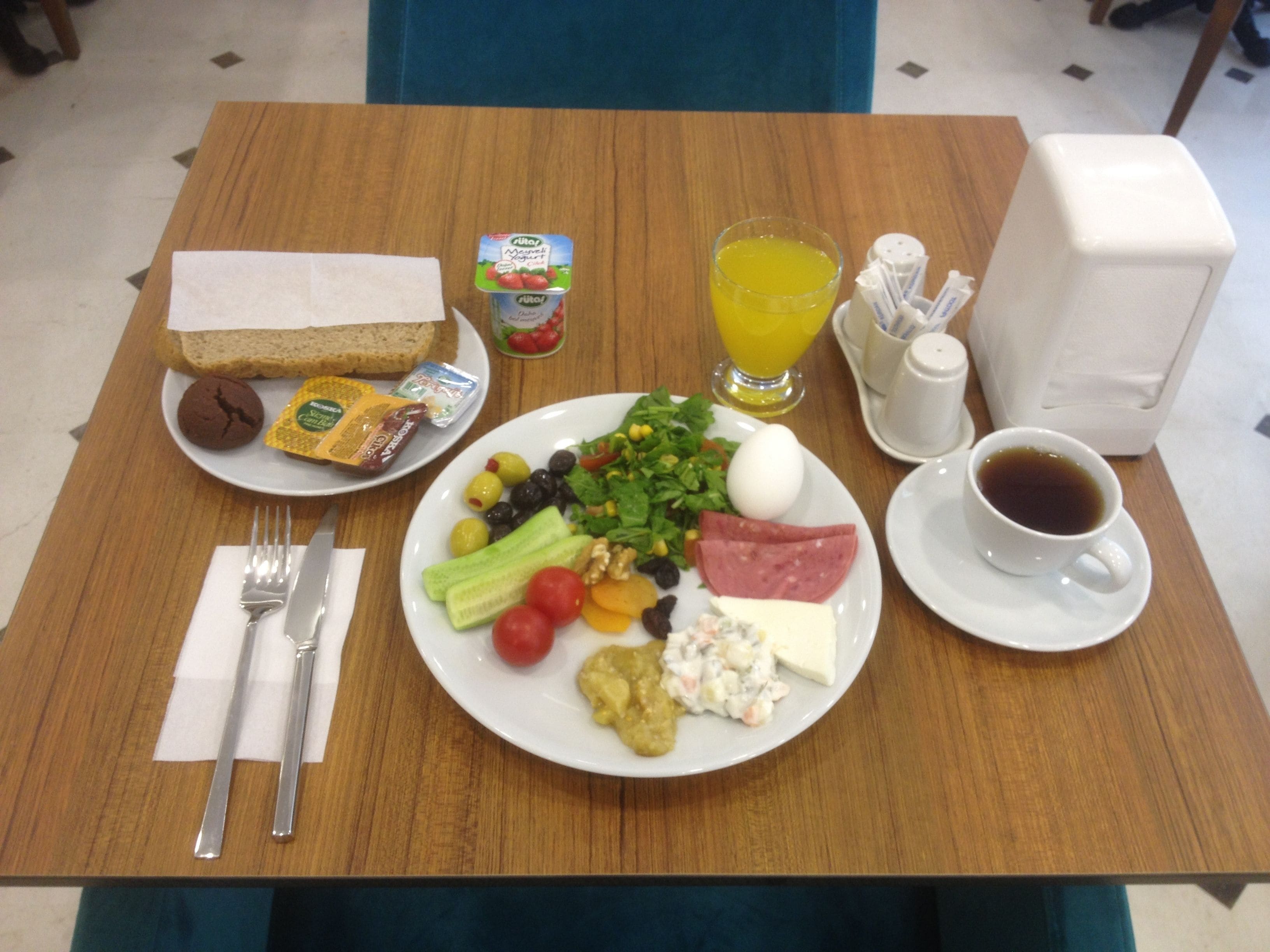 Una mesa de desayuno con un plato de comida, un vaso de jugo de naranja, una taza de café y un sándwich.