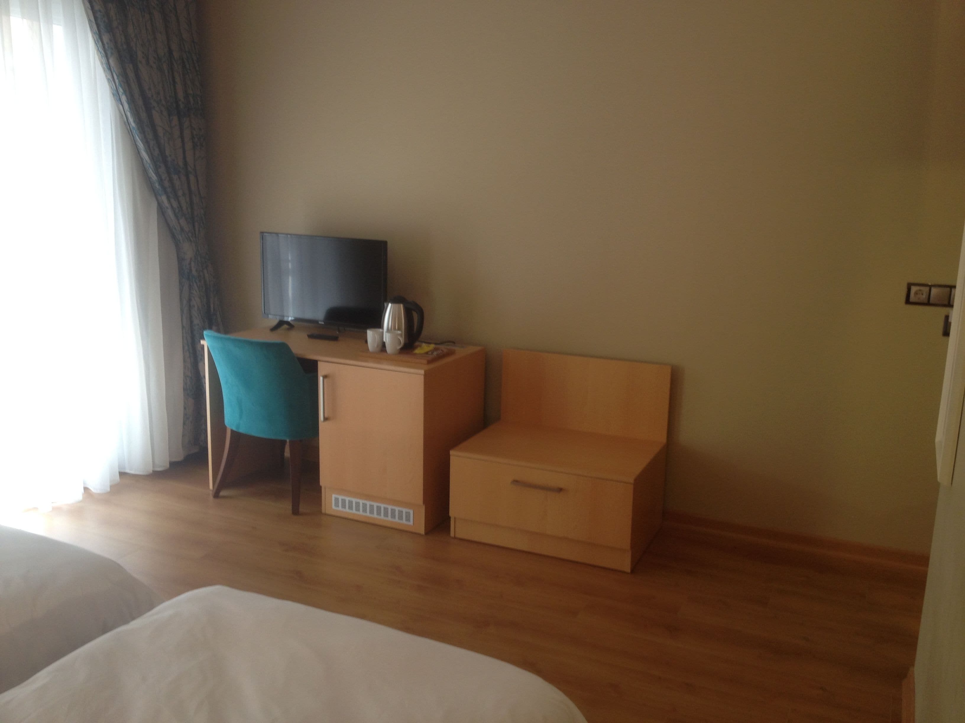 Une chambre d’hôtel avec un bureau en bois, une télévision, une chaise et un lit.