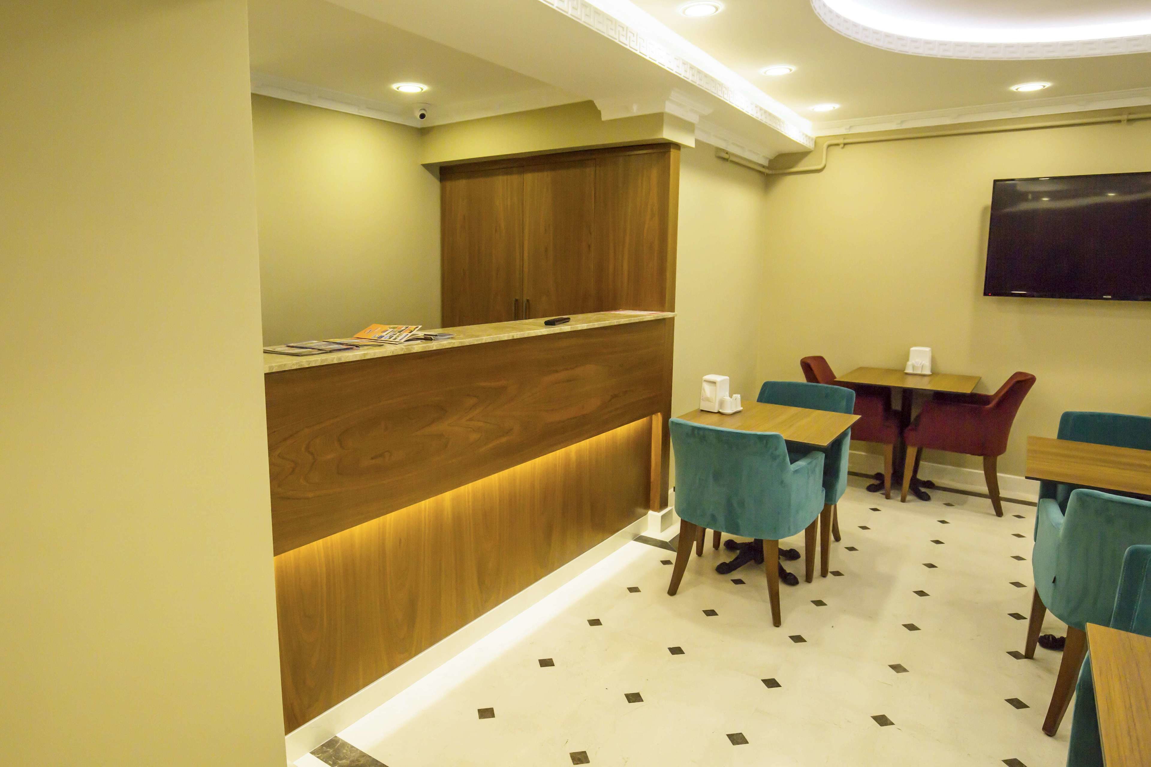 A reception area with a wooden counter, a flat-screen TV mounted on the wall, and several tables and chairs.