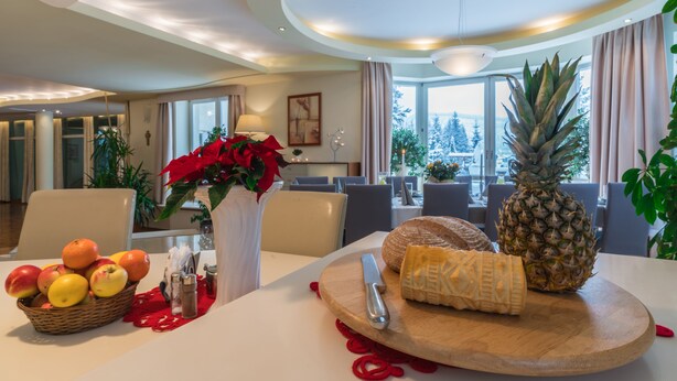 Un comedor con una mesa dispuesta para una comida, que incluye frutas, queso y una piña.