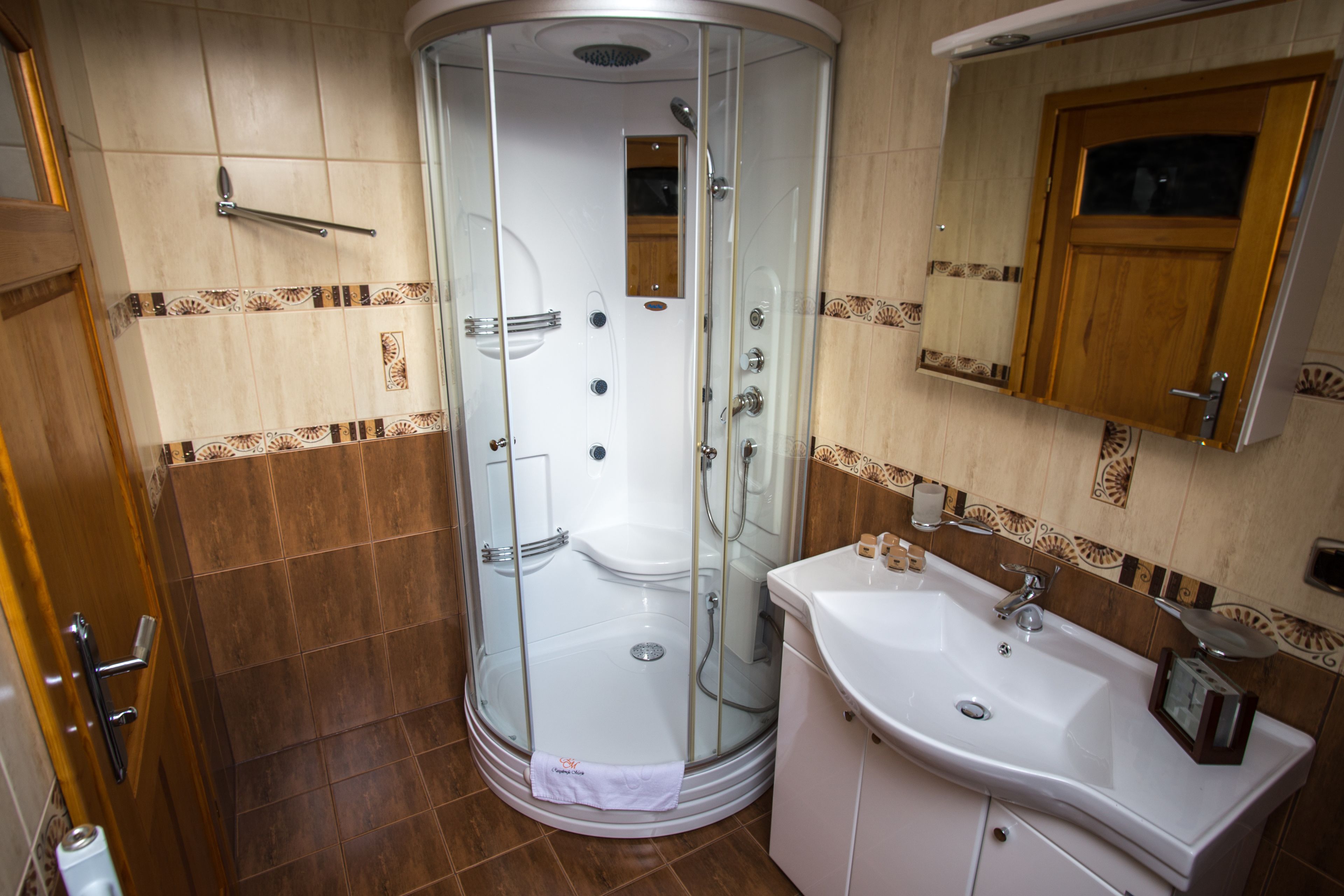 A bathroom with a glass-enclosed shower, a sink, and a mirror.