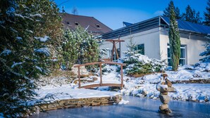Un espacio exterior cubierto de nieve con un puente de piedra, un columpio de madera y una escultura de nieve.