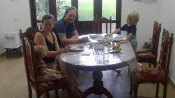 Spisebord med stole, en drikkevandstilskuer og et vindue med udsigt til grøn vegetation.