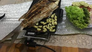 A dining table with a whole fish, garlic cloves, and various dishes. - Lavender Home Rest (Thissamaharama)