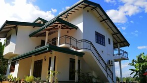 A two-story house with a balcony, a staircase, and potted plants. - Lavender Home Rest (Thissamaharama)