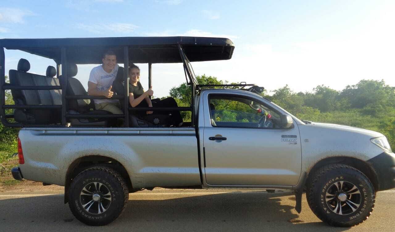 Una camioneta pickup plateada con una estructura de carga en el techo y dos pasajeros adentro.