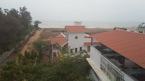 A coastal building with a red-tiled roof, a white facade, and a view of the sea. - Meya Beach Walk Hotel (Tirukalukundram)