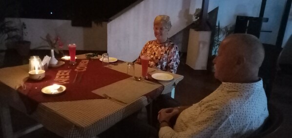 Una mesa de comedor con un posavasos rojo, velas y un vaso de bebida roja.