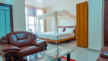 A bedroom with a four-poster bed, a leather armchair, and a glass coffee table.