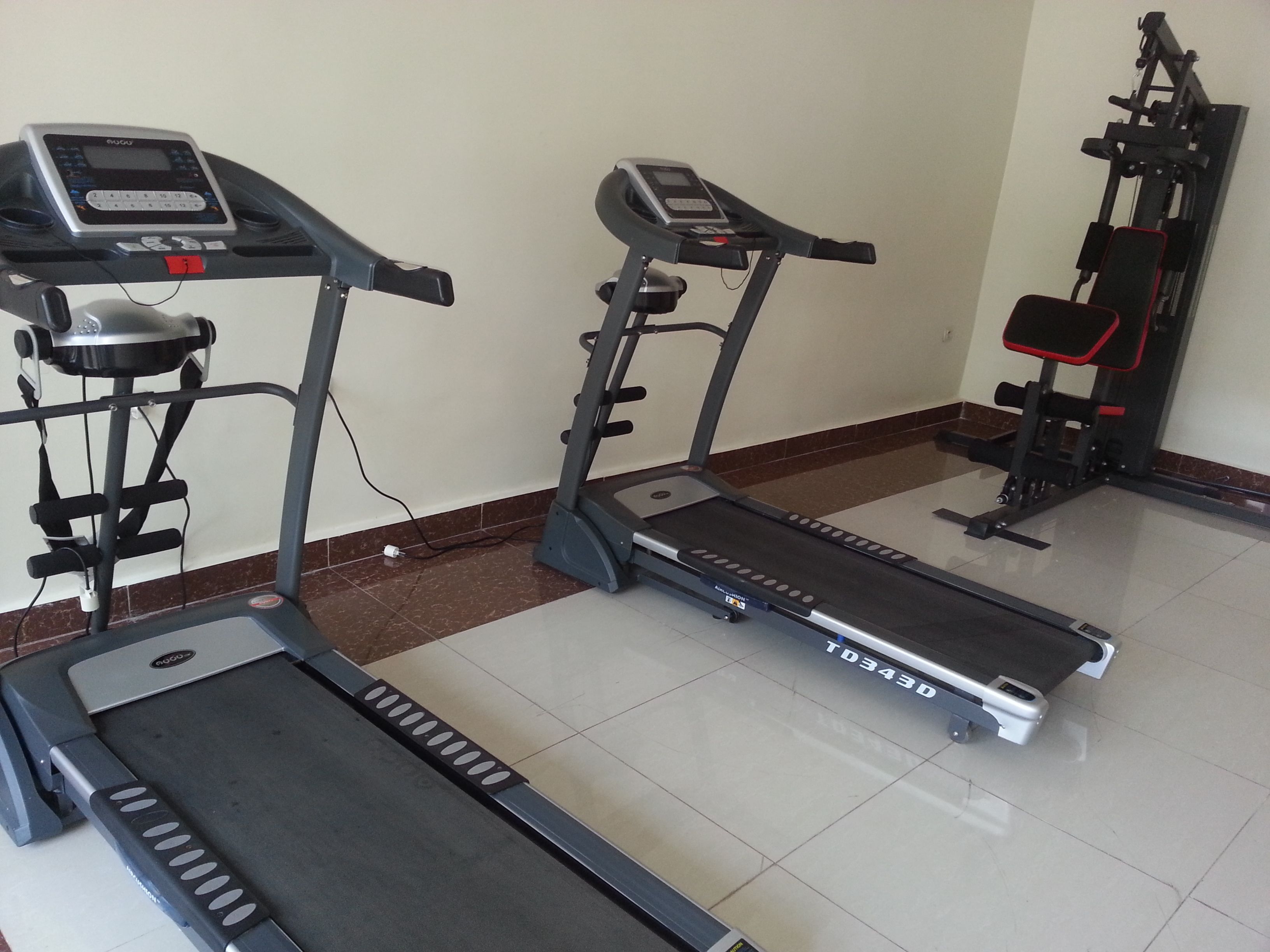 Un gimnasio con cintas de correr, una bicicleta estática y una máquina de pesas.