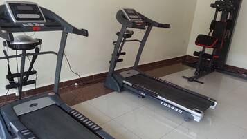 Un gimnasio con cintas de correr, una bicicleta estática y una máquina de pesas.