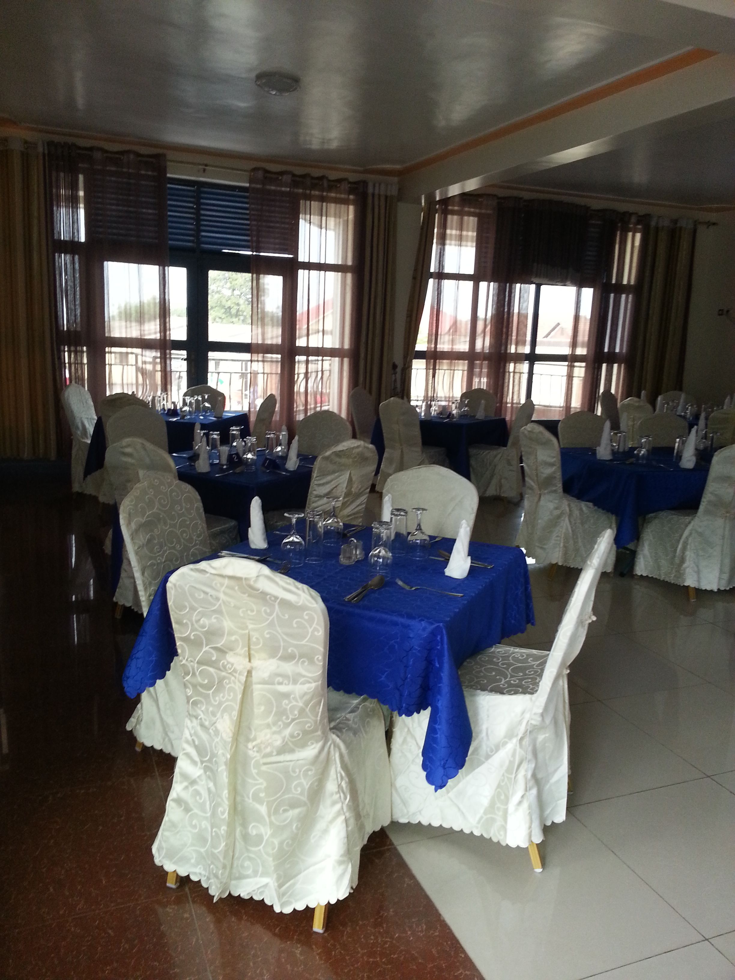 A banquet hall with tables set for a formal event, featuring white chairs and blue tablecloths.