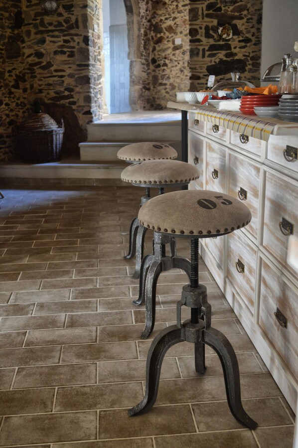 A kitchen with stone walls, a brick floor, and a bar stool with a number '05' on it. - La Casa della Filanda (Belmonte Calabro)