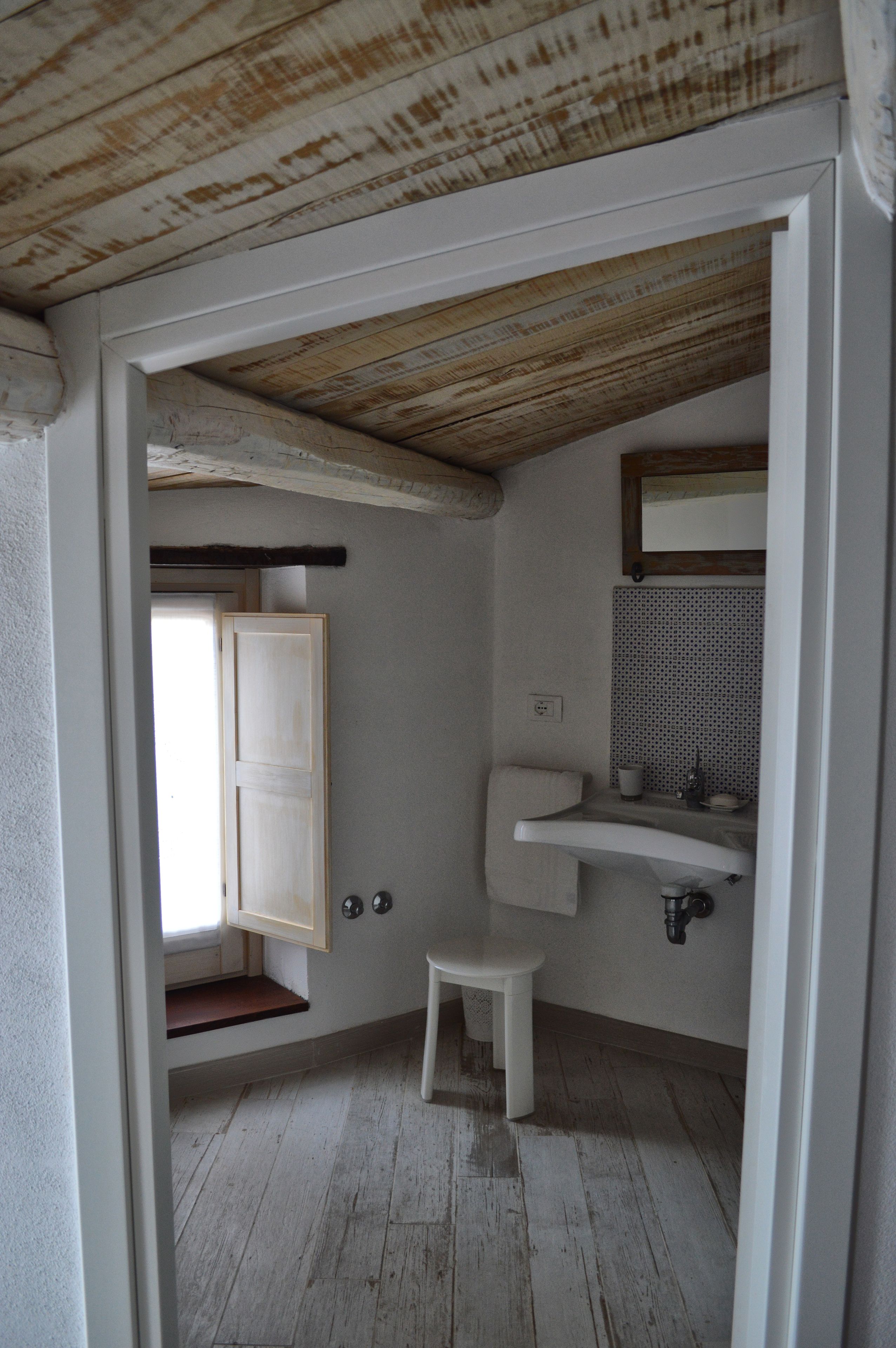 Une petite salle de bain rustique avec un plafond en bois, un lavabo blanc et des toilettes.