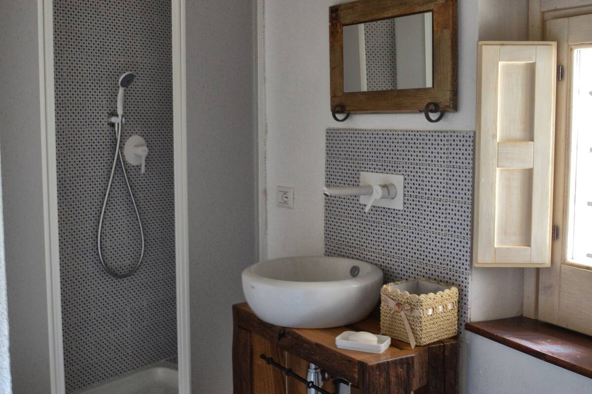 A bathroom with a shower, sink, and wooden cabinet.